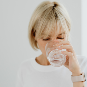 Woman drinking a glass of water to stay hydrated as part of recurrent UTI treatment and prevention