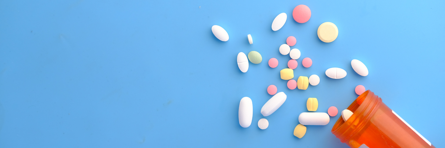 Antibiotic resistant UTI concept with colorful pills spilling from an orange prescription bottle on a blue background