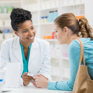 Pharmacist showing a customer a medication box, illustrating whether a pharmacist can prescribe antibiotics for a UTI